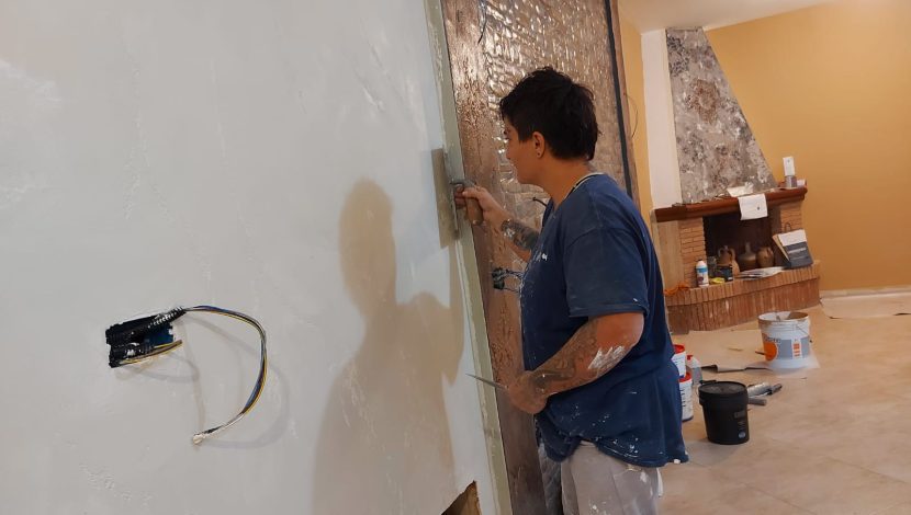 Una persona che lavora con una spatola su un muro bianco, facendo un'attività di tinteggiatura