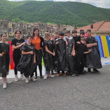 Un gruppo di ragazzi in posa fuori da una città, con dietro dei pannelli colorati