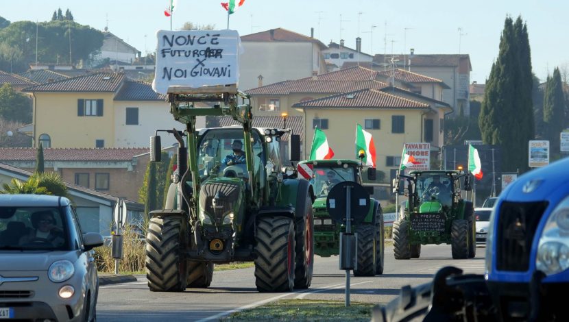 Trattori che sfilano per la strada, sormontati da bandiere italiane