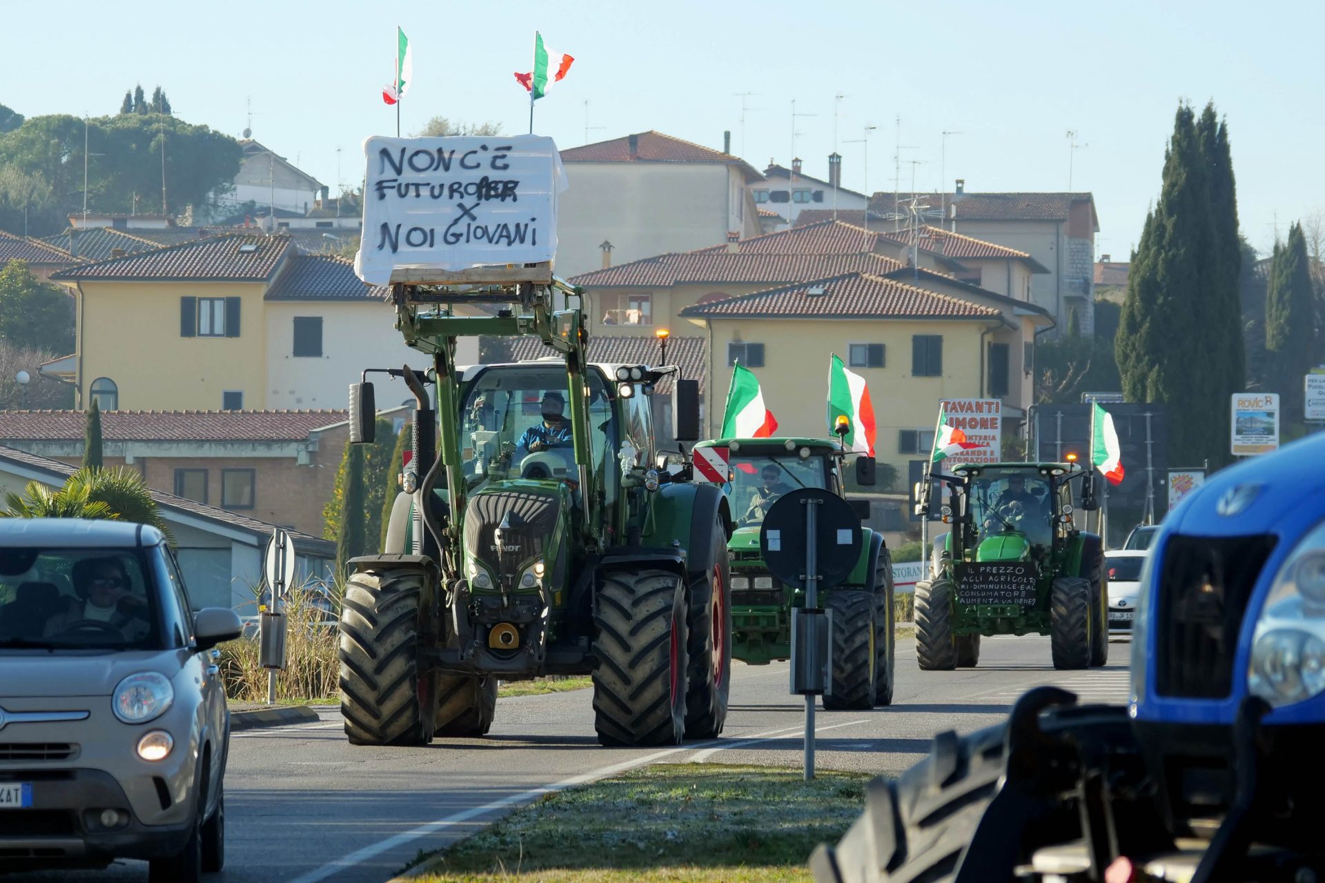 Trattori che sfilano per la strada, sormontati da bandiere italiane