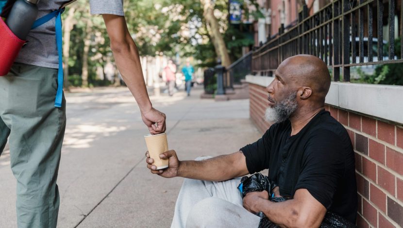 Un uomo dona dei soldi a un homeless per strada