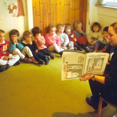 educatrice legge un libro ai bimbi dell'asilo
