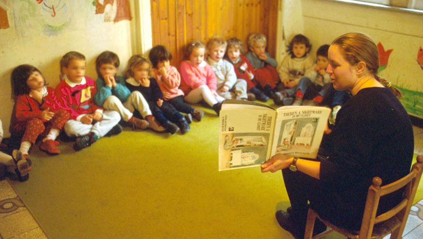 educatrice legge un libro ai bimbi dell'asilo