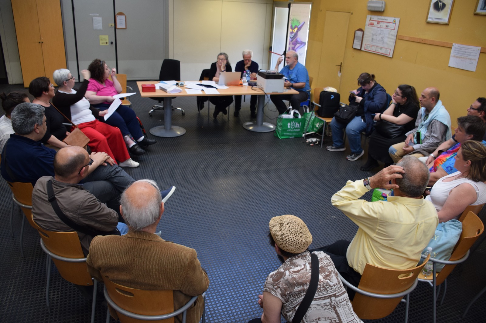 Persone in cerchio, sullo sfondo c'è un tavolo da conferenza 