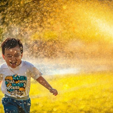 bambino asiatico che corre giocando con l'acqua