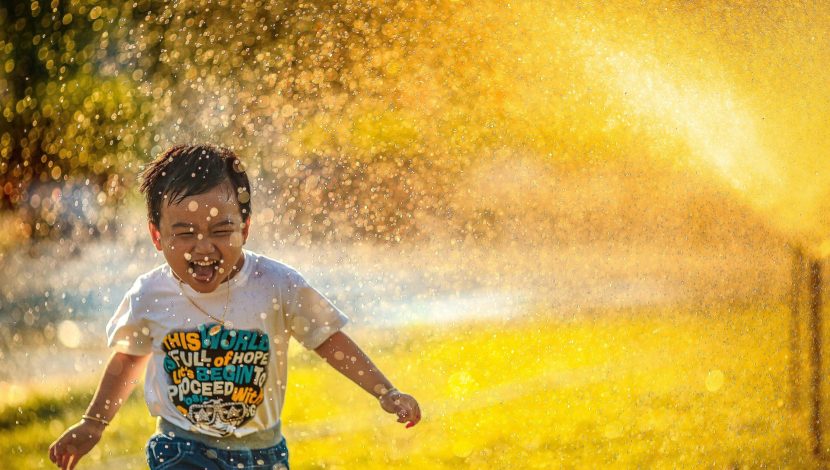 bambino asiatico che corre giocando con l'acqua
