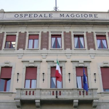 La facciata di un edificio, sul balcone c'è una bandiera italiana e una europea, in alto c'è scritto "Ospedale maggiore"