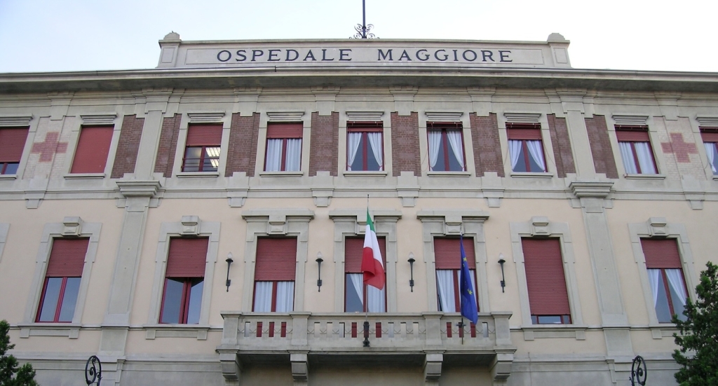 La facciata di un edificio, sul balcone c'è una bandiera italiana e una europea, in alto c'è scritto "Ospedale maggiore"